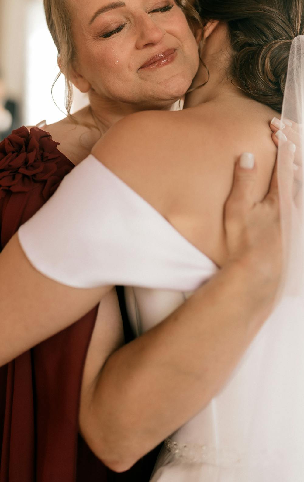 Brautmutter umarmt gerührt ihre Tochter am Hochzeitstag