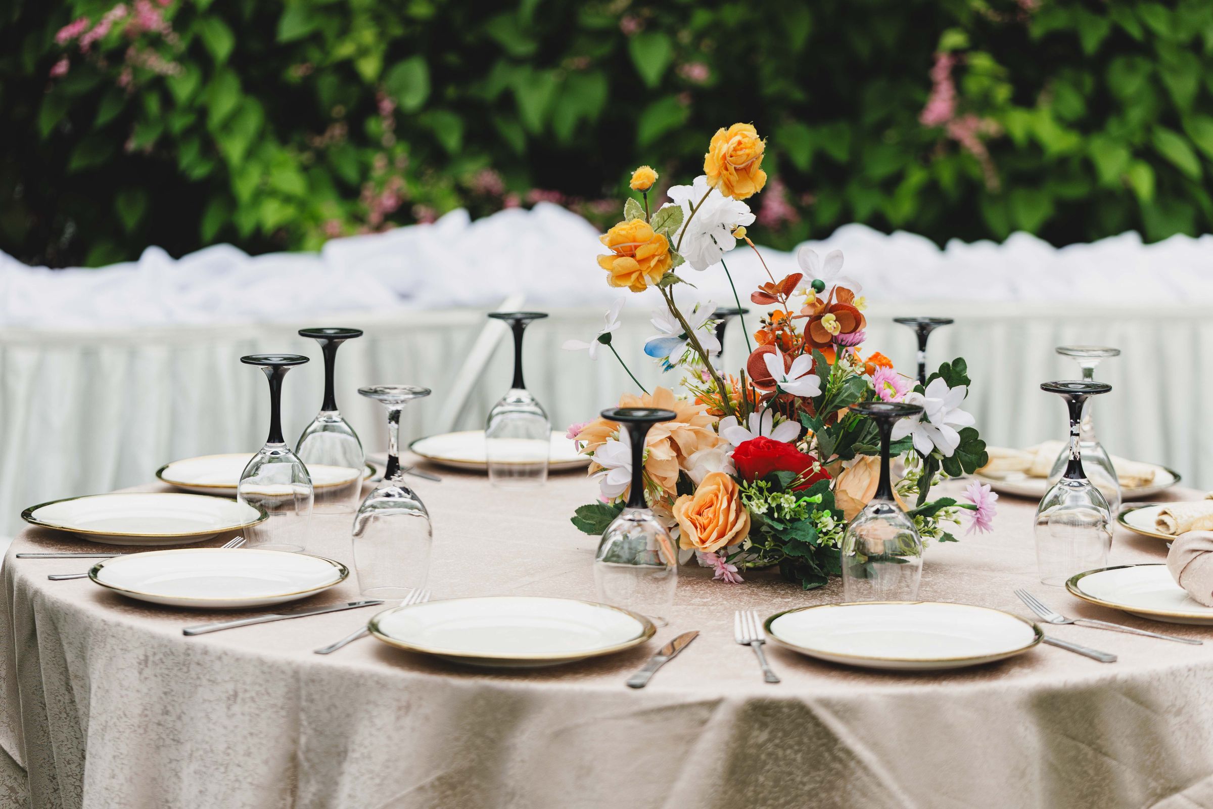 Festlich gedeckte Hochzeitstafel mit Blumengesteck im Freien